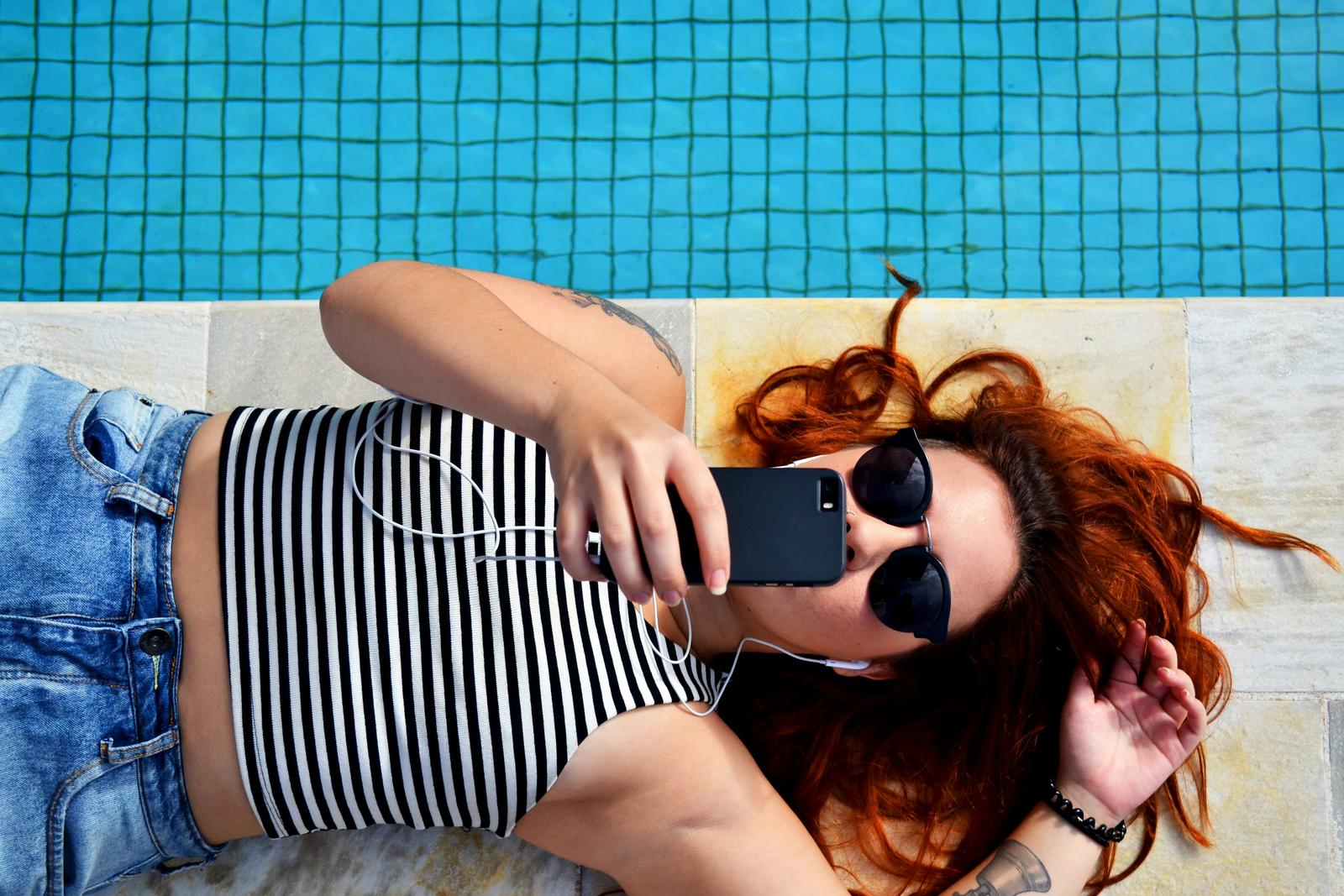 Person relaxing by the pool with phone
